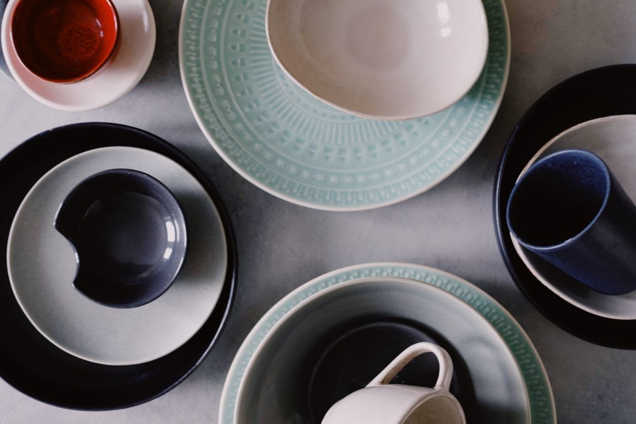 Artistic flat lay of colorful ceramic plates, mugs, and bowls on a table.
